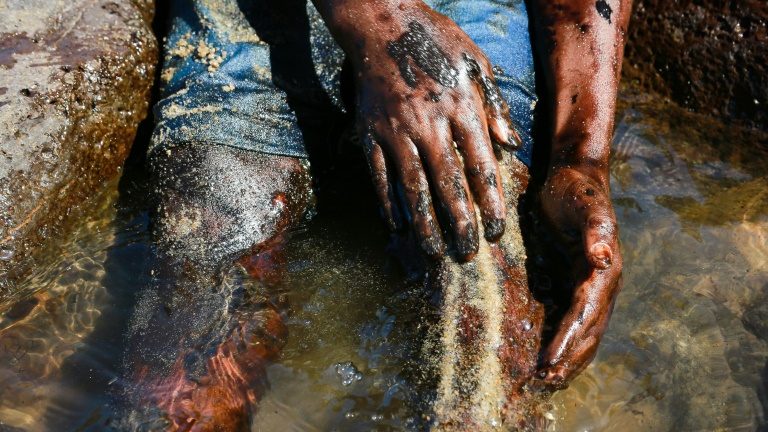 Menino tenta limpar petróleo de seu corpo em Cabo de Santo Agostinho, Pernambuco, em 21 de outubro - AFP