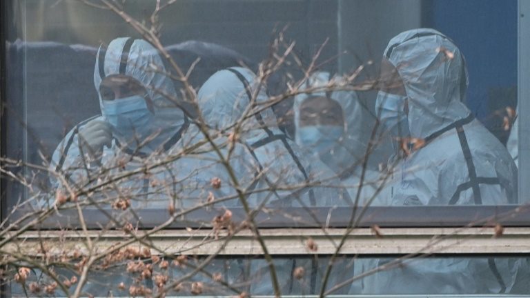Membros da delegação da Organização Mundial da Saúde investigando a origem da covid-19 vestidos com roupas de proteção, em Wuhan, 2 de fevereiro de 2021 - AFP/Arquivos