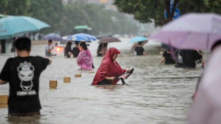 Pessoas presas nas águas em uma rua em Zhengzhou, centro da China, em 20 de julho de 2021 - AFP