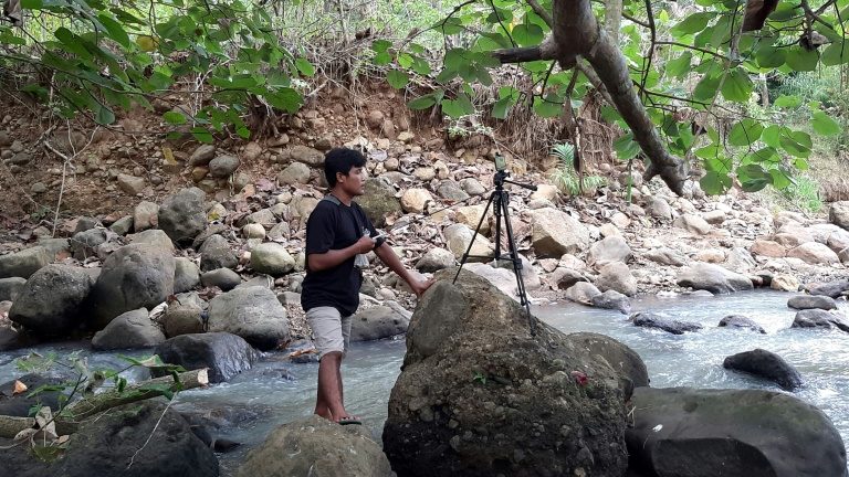 O YouTuber Siswanto, da Indonésia, gravando um de seus vídeos junto a um rio da comunidade agrícola de Banyuwangi - AFP