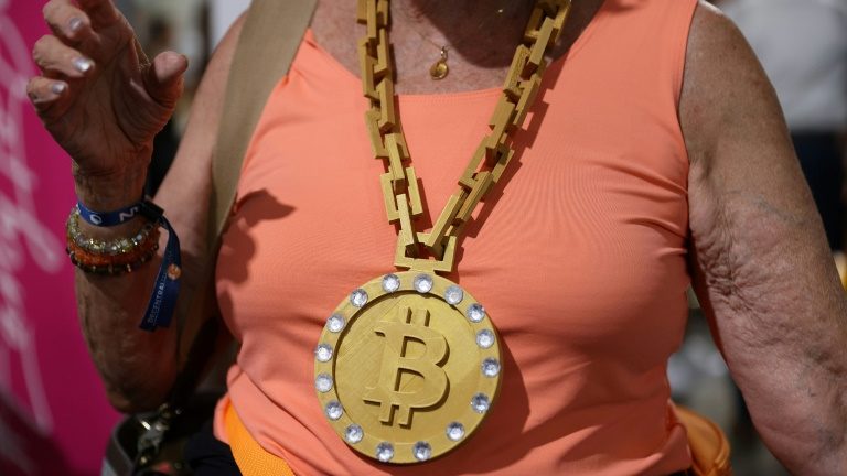 Participante da convenção do Bitcoin de 2021 exibe um maxicolar com a logo da criptomoeda, no Mana Convention Center de Miami, em 3 de junho de 2021 - GETTY IMAGES NORTH AMERICA/AFP/Arquivos