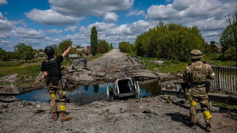 Soldados da unidade de forças especiais ucranianas Kraken falam com um homem em uma ponte destruída na estrada perto da vila de Rouska Lozova, ao norte de Kharkiv, em 16 de maio de 2022 - AFP